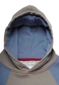 Huppu kahdesta sävystä koostuvassa harmaan ja sinisen puuvillaneuleessa. Sisältä pehmeä, kauluksessa punainen yksityiskohta ja sisällä ommeltu etiketti.