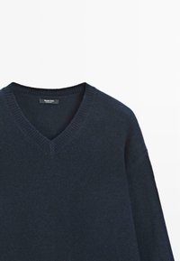 Marineblauwe v-hals trui met een geribbelde kraag en textuurgarens. Heeft een relaxte pasvorm en subtiele stikdetails.