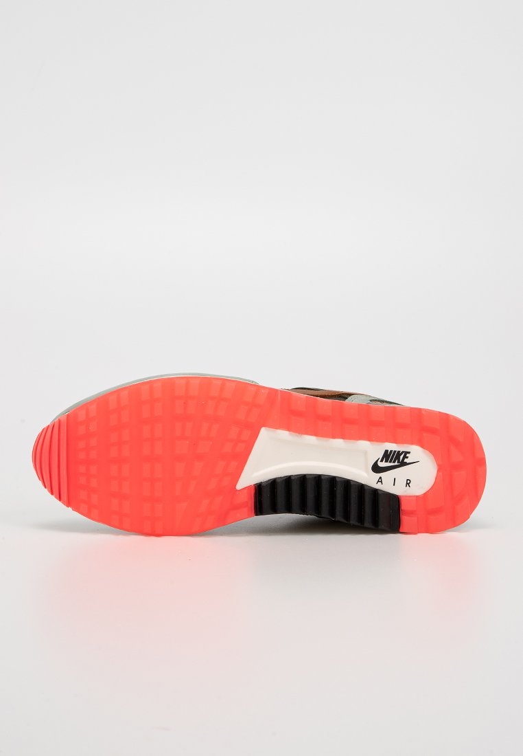 Sole butów sportowych Nike Air w czerni i jaskrawym pomarańczu. Teksturowany gumowy wzór zapewniający przyczepność. Zawiera logo Nike, z białym akcentem na śródstopiu.