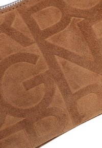 Pochette en daim marron avec motif de lettres en relief, texture lisse et fermeture éclair en argent. Forme rectangulaire avec des lignes épurées.
