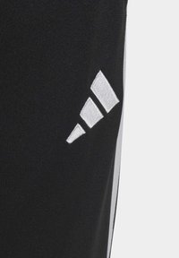 Čierne funkčné športové oblečenie s bielou vyšitou logom Adidas. Elegantný dizajn s textúrovaným povrchom a bočnými akcentmi.