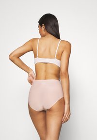 Pink ribbed bra with adjustable straps, paired with high-waisted, smooth fabric panties, showcasing a seamless design and minimalist style.