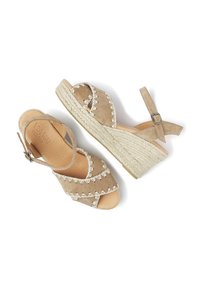 Beige suede wedge sandaaltjes met een gevlochten jute zool, voorzien van kruislings-cross straps en scalloped stikselaccenten. Gesp sluiting bij de enkel.
