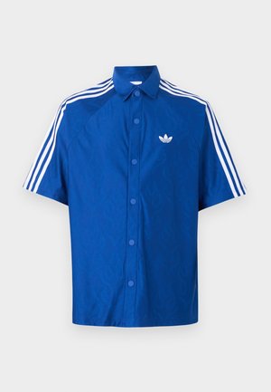 Sinine lühikeste varrukatega nööpide ja valge Adidas logo rinnal ning kolm valget triipu, mis kulgevad mööda õlgu ja varrukaid.