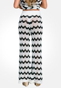 Pantaloni a gamba larga in un motivo a zigzag bianco e nero in maglia. Presentano una vita alta e una trama aperta texturizzata per garantire traspirabilità.