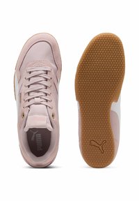 Zapatillas Puma con un upper sintético rosa, acentos blancos y una suela de goma texturizada. Presentan un cierre de cordones y una marca en la lengüeta.