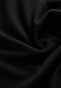 Tessuto nero lavorato a maglia che presenta una consistenza liscia e morbida con una leggera elasticità. Le fibre sono intrecciate in modo compatto, creando una superficie uniforme.