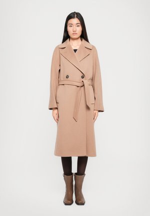 Beige wool coat with a double-breasted design, large lapels, a waist tie, and side pockets, paired with brown ankle boots.