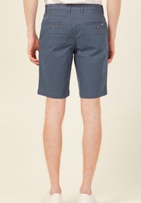 Mörkblå shorts för män tillverkade av bomull. Har två bakfickor med knappstängning och en rak skärning vid mitten av låret.