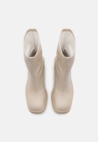 Beige Leder-Ankelstiefel mit glatter Oberfläche, leicht geschwungener Silhouette und abgerundeter Spitze. Die Sohlen sind aus einem leichteren synthetischen Material.