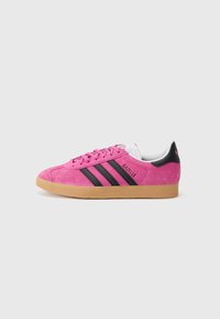 Pink suede sneaker with black stripes, rounded toe, and rubber gum sole. Features white accents and stitched detailing on the side.
