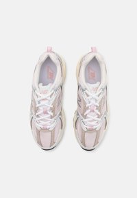 Baskets de sport rose clair et grises avec tige en maille, semelle en caoutchouc contrastante, lacets blancs, et onglet de talon accentué.