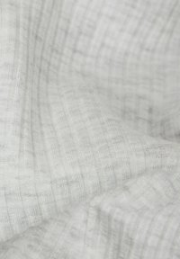 Textilní vzorek v bílé barvě s jemnou žebrovanou strukturou, s lehkým šedým pruhovaným vzorem. Měkký a lehký materiál.