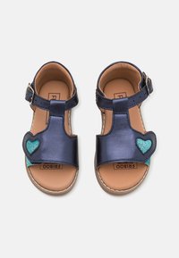 Marina lädersandaler med T-rem-design, med en glittrande teal-hjärta som dekoration och en brun lädersula. Justerbar spänne.