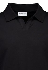 Schwarzes Polohemd mit entspannter Passform, V-Ausschnitt-Kragen und glatter Textur. Im Nackenbereich ist ein Etikett mit der Aufschrift "LINDBERGH" angenäht.