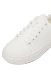 Biała niskoprofilowa sneaker wykonana z gładkiego syntetycznego materiału, z płaskimi sznurówkami, okrągłym noskiem, przeszytymi akcentami i gumową podeszwą.