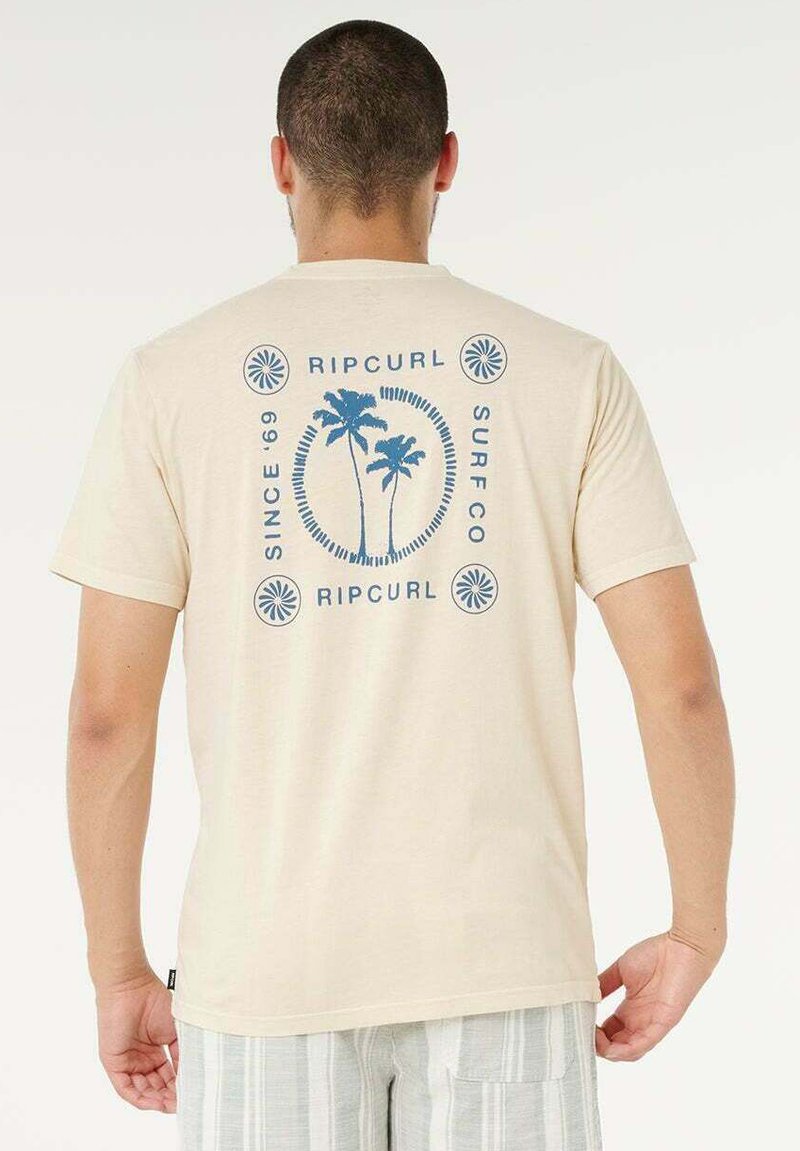 T-shirt beige in cotone con design grafico blu che presenta palme, motivi circolari e il testo "RIP CURL SURF CO" al centro della schiena.