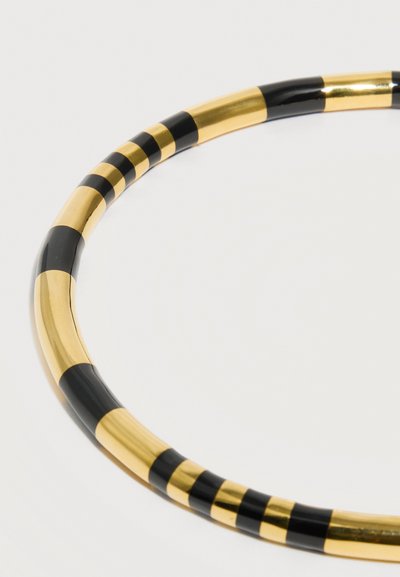 Bracelet jonc métallique rayé or et noir avec une finition lisse et brillante sur un fond blanc uni.