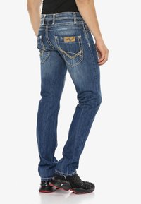 Blauwe denim jeans met een rechte pijp, voorzien van achterzakken met stikseldetails en een leren label met merknaam op de tailleband.