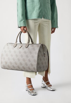 Grijze patroon duffelbag met een gladde textuur, dubbele handgrepen, goudkleurige hardware en ritsluiting, tentoongesteld naast lichtgroene broeken en zilveren schoenen.