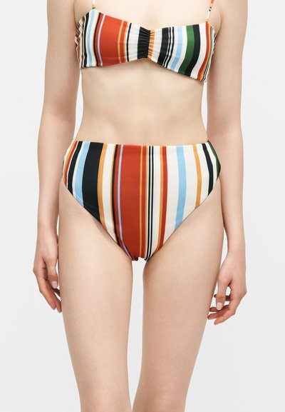 Femme portant un bikini rayé vertical multicolore, culotte taille haute et haut bandeau avec fines bretelles.