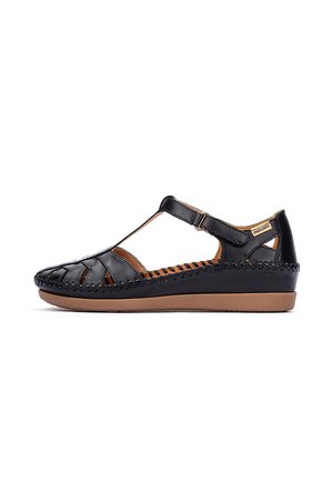 Sandalia de cuero negro con puntera cerrada y diseño tejido, con correa ajustable en el tobillo, plantilla acolchada y suela baja tipo cuña en tono marrón.