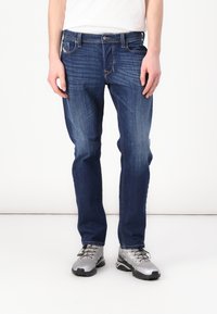 Jeans din denim de culoare albastru închis, cu croială dreaptă, prezentând un design clasic cu cinci buzunare, ușor uzate și accente din metal argintiu.