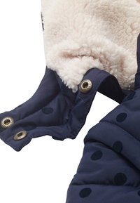 Navy blue padded coat featuring a soft cream fleece lining, snap closures, and black polka dot patterns on the outer fabric.