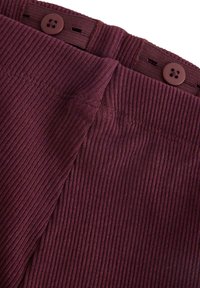 Maroon corduroy-kangas vyötärö kahdella ruskealla napilla. Teksturoitu pinta sisältää pystysuorat urat. Yksityiskohtainen ompelu reunan ympäri.