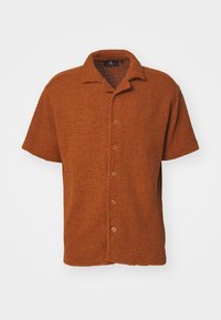 Chemise marron à manches courtes avec boutons, en tissu tricoté texturé et col pointu sur fond blanc.