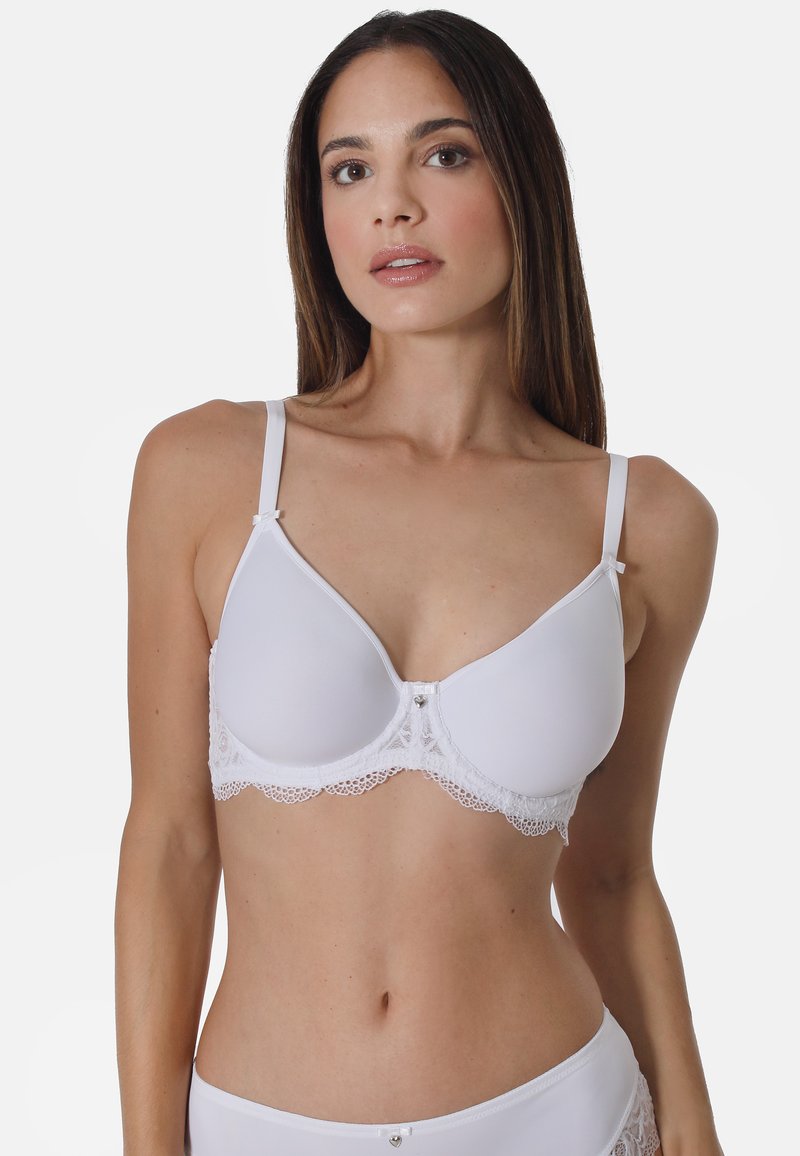 White bra featuring smooth fabric and a lace trim along the bottom. Adjustable straps and a small decorative accent at the center.