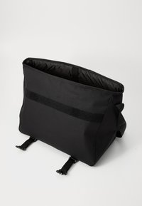 Sac messager noir en tissu durable, doté d'une doublure intérieure douce, de bretelles réglables et d'un accent velcro sur le devant.