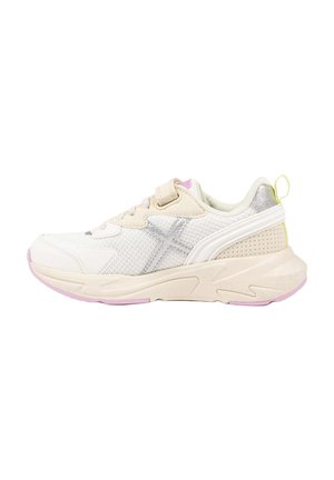 Zapatilla deportiva blanca y beige con tejido de malla, logo de cruz plateado, suela gruesa, cierre de velcro y detalles en rosa claro en la suela exterior.