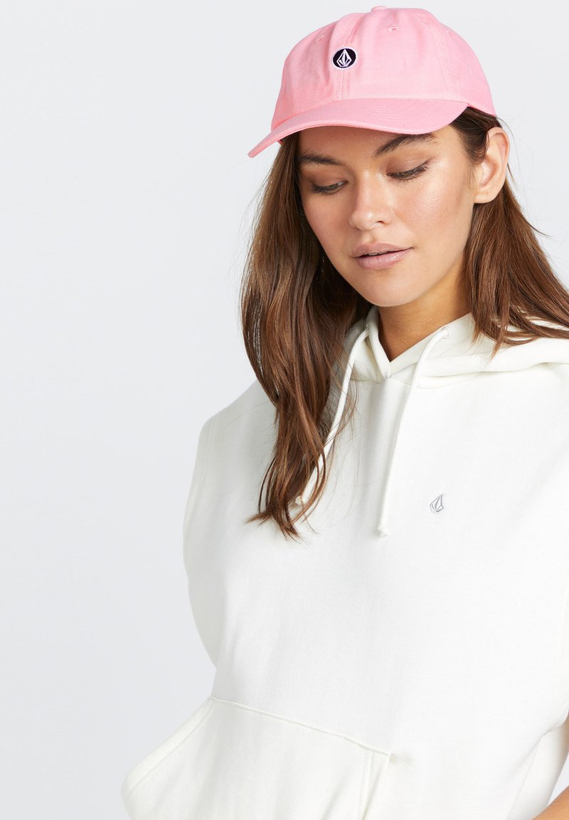 Roze baseballcap van katoen met een afgeronde kroon en een geborduurd logo aan de voorkant. Gekozen in combinatie met een witte hoodie met een kangoeroezak.