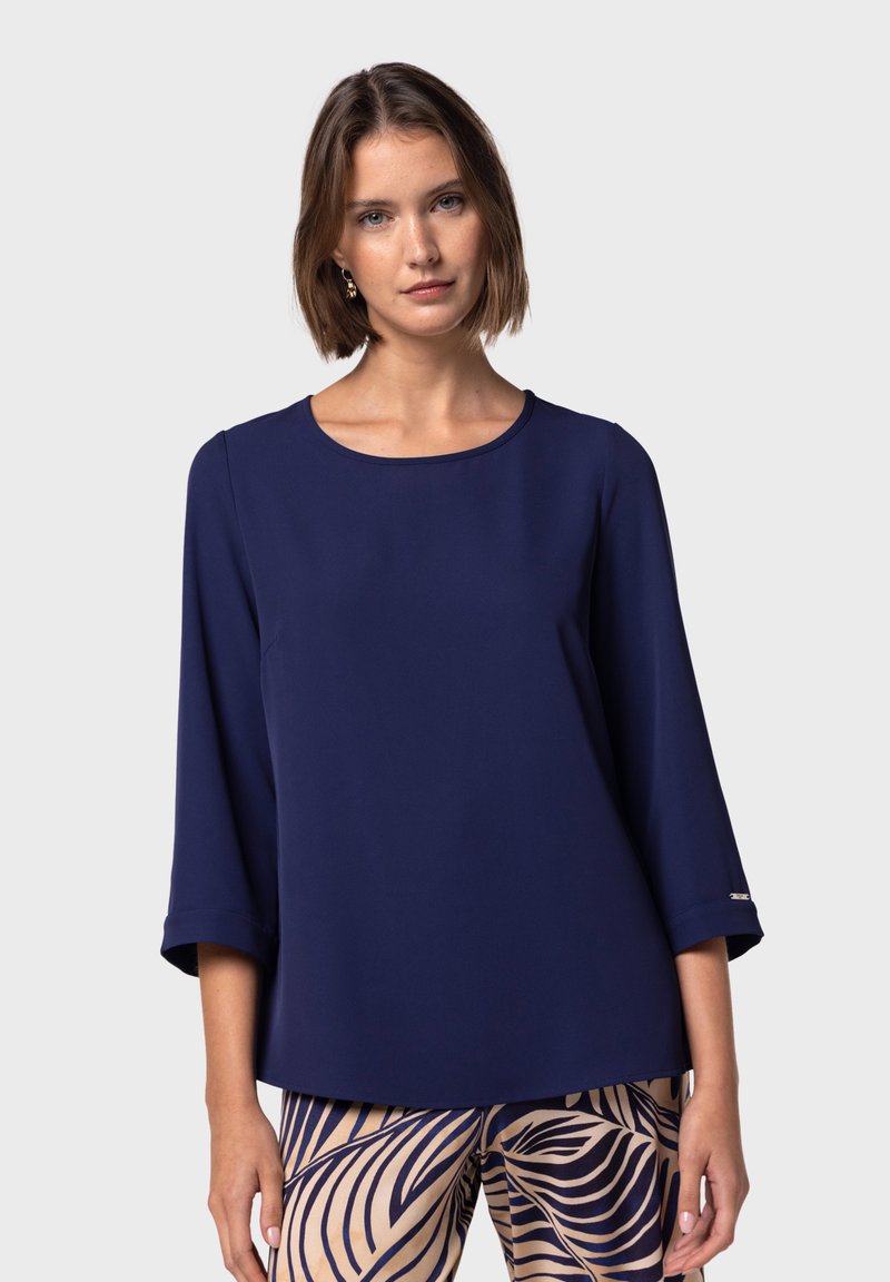 Top blu navy in tessuto leggero con scollatura rotonda e maniche a tre quarti; presenta un dettaglio argentato all'orlo della manica.