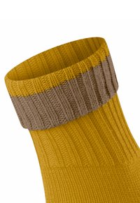 Chaussette tricotée avec un corps jaune à côtes et un revers marron à côtes, mettant en valeur une finition texturée.