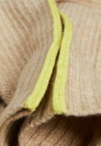 Tessuto a coste beige con una morbida texture, accentuato da un bordo con zip gialla brillante lungo il bordo.