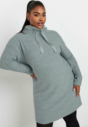 Vestido con capucha de color gris claro y textura suave, con mangas acanaladas y cierre con cordón. La longitud cae por encima de la rodilla.