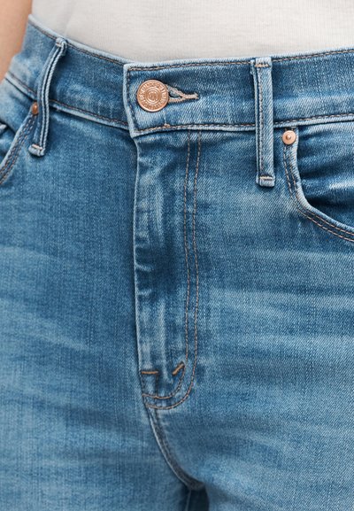 Világoskék farmernadrág, magas derékkal, réz gombos záródással és narancssárga varrási részletekkel. Egyenletes textúra finom kifakítással.