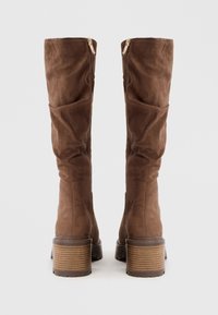 Brown suede knee-high boots with a textured surface, side zippers, and a stacked heel featuring horizontal grooves.
