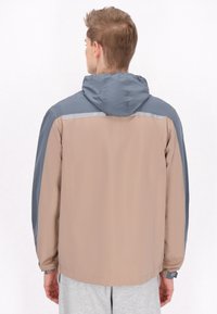 Jachetă pentru bărbați cu un design bicolor în bej și gri, prevăzută cu glugă, manșete elastice și accente reflectorizante pe umăr.