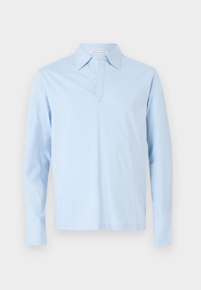 Camisa polo de mangas compridas azul claro, feita de algodão suave. Apresenta um colarinho clássico e uma pala com um detalhe de costura subtil na frente.