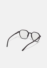 Lunettes octogonales noires avec verres transparents. Monture légère avec des branches fines et des détails matériels subtils. Design minimaliste.