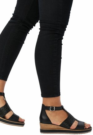 Zwarte sleehak sandalen met enkelbandje, uitgesneden bloemmotief op het bovenwerk en een houtnerftextuur op de sleehak.