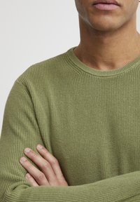 Grüner Strickpullover mit strukturiertem Muster und Rundhalsausschnitt, mit gerippten Kanten und lockerer Passform.