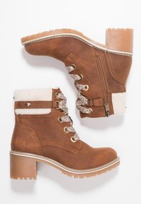 Bottines en cuir marron avec col en polaire texturé, semelle épaisse, lacets décoratifs, fermeture éclair sur le côté et talon carré.