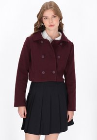 Burgundská zkrácená bunda s dvojími knoflíky, velkými knoflíky a záševkovým límcem. V kombinaci s černou plisovanou sukní.