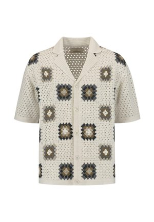 Chemise à manches courtes avec un design en crochet crème et des motifs carrés en marron foncé, gris et beige. Elle possède un col et une fermeture à boutons.
