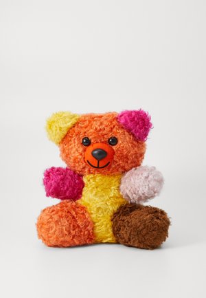 Krāsains mīkstā teddy lācis ar oranžu, dzeltenu, rozā un brūnu vilnu. Apaļa forma ar melnām acīm un smaidošu muti. Mīksta, strukturēta virsma.