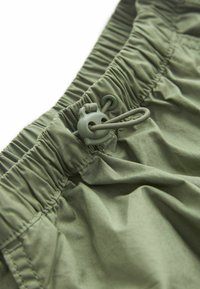 Olivgröna shorts med elastisk midja, rynkad textur och snörning för justerbar passform. Mjukt, lättviktigt tyg.